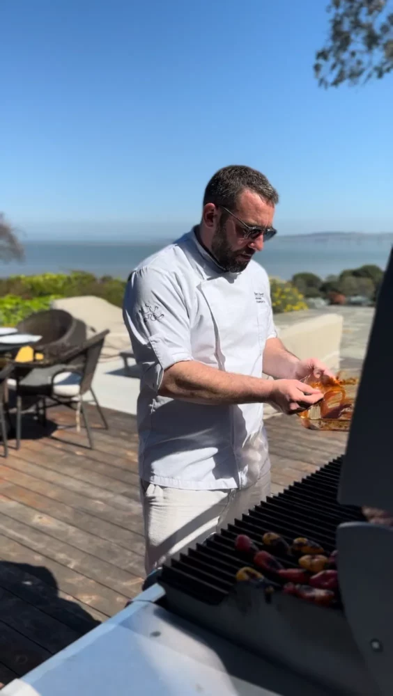 Chef à domicile cuisinant en extérieur face à la mer en Normandie